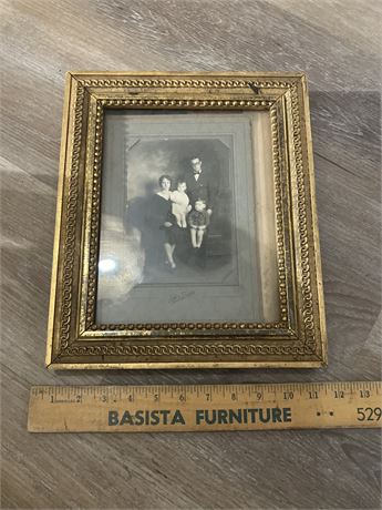 antique black and white family portrait in an ornate gold-colored frame.