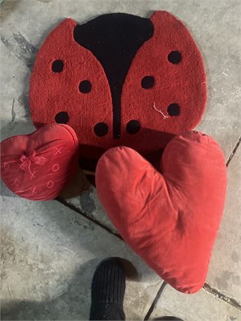 Ladybug-shaped plush item, likely a pillow, with two heart-shaped pillows
