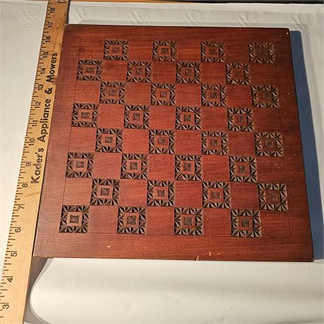 Wooden chessboard with carved designs on each square