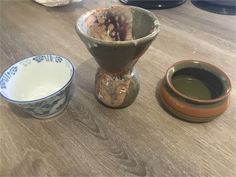 Three different pieces of handmade ceramic pottery, likely bowls or cups.