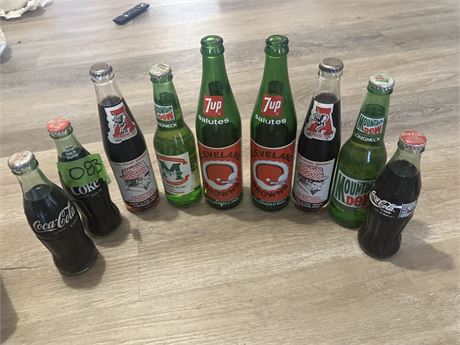 Collection of vintage Coca-Cola, Mountain Dew, and 7 Up glass soda bottles, whic