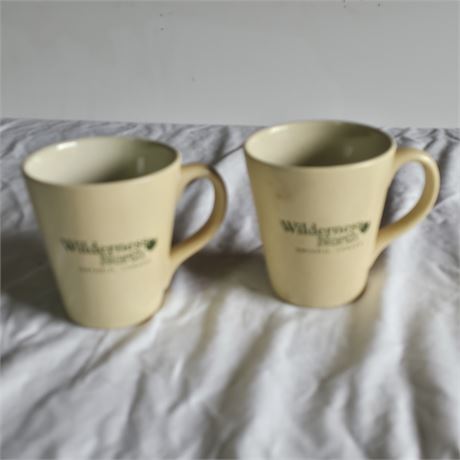 Two ceramic coffee mugs with a logo that appears to read "Wilderness North
