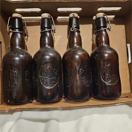 Four amber-colored Grolsch-style swing-top bottles,